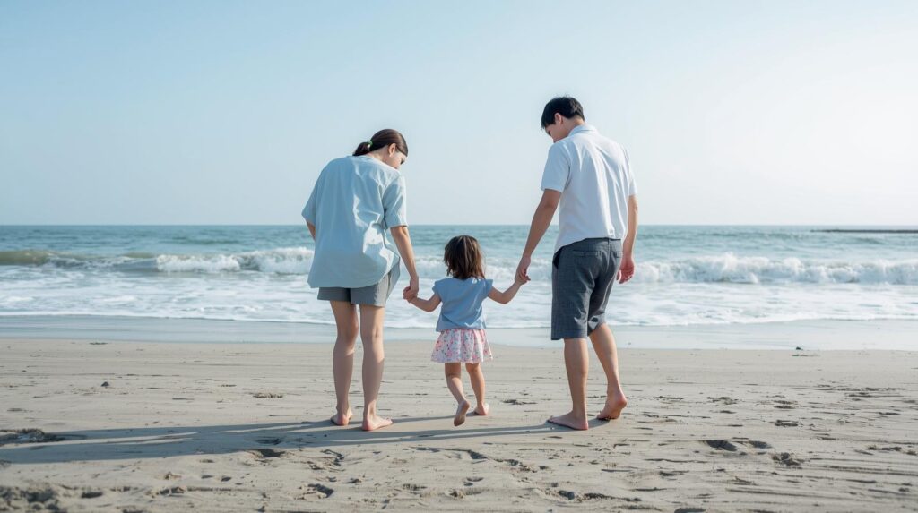 海岸で親子が手をつなぎながら散歩している画像
