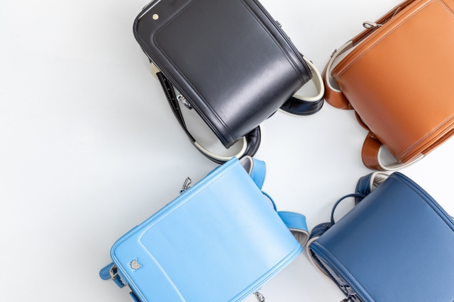 小学生がランドセルを床に置いて並べている画像