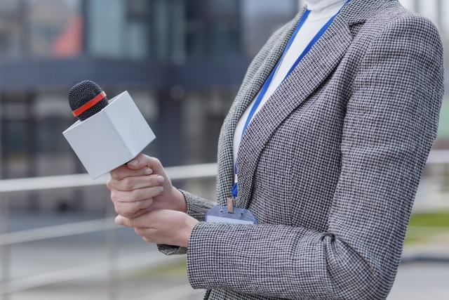 マイクを向けてインタビューをする女性の画像