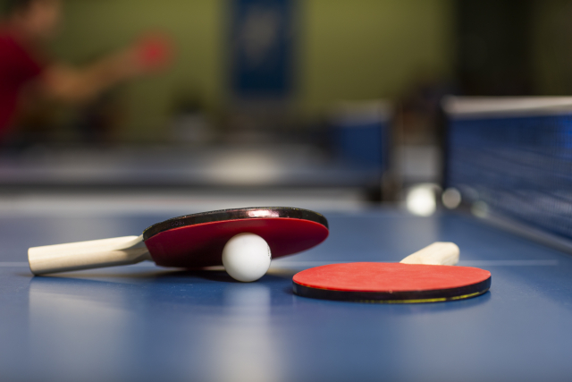 卓球台の上にラケットとピンポン玉が置いてある画像
